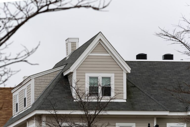 Dormer windows on the sloped shingle roof of a newly built family house on a winter day