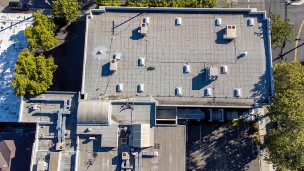 Aerial view of a flat commercial rooftop with air vents and air conditioning HVAC units