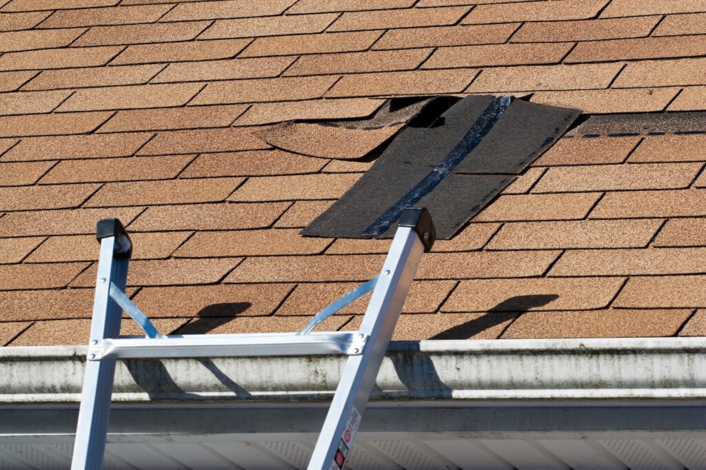Fixing damaged roof shingles.  A section was blown off after a storm with high winds causing a potential leak.