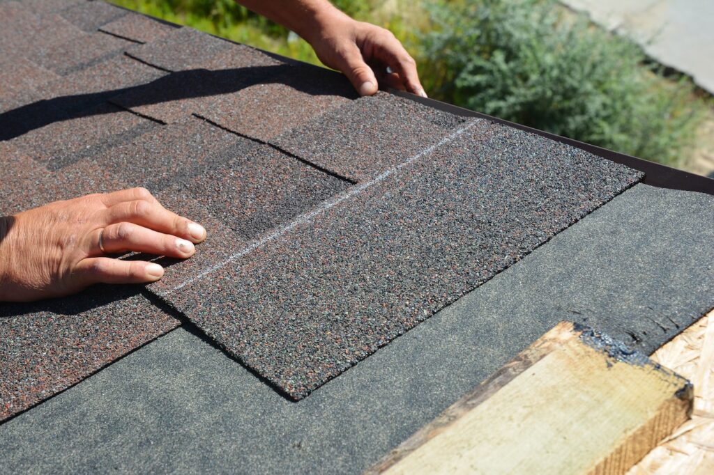 Asphalt Shingles Installation. Roofer Contractor Installing Asphalt Shingles on House Roofing Construction