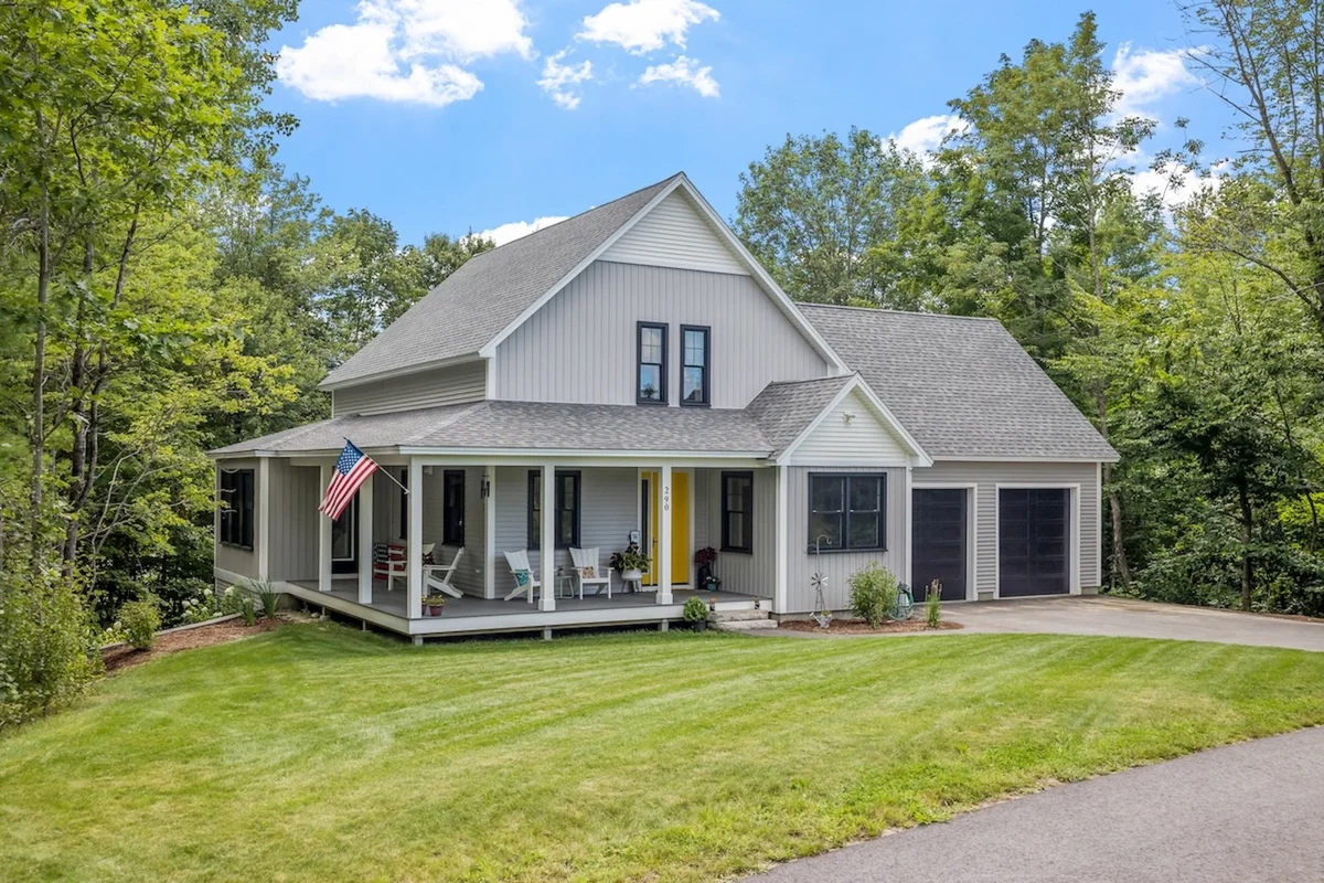 Modern custom new England colonial home with an American flag on a sunny day