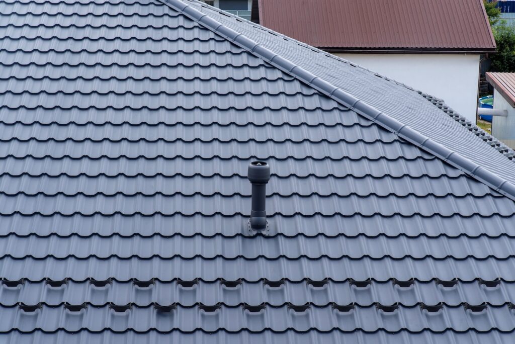 Plastic roof vent pipe on gray metal tile roofing