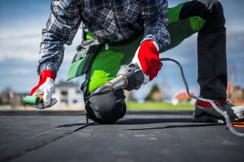epdm rubber roofing worker using heat gun on top of roof