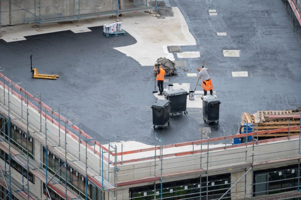 flat roof coating options workers applying bitumen