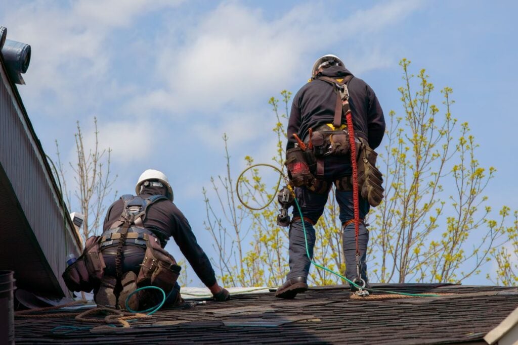 two workers repairing shingles roof