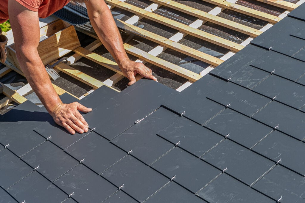Craftsmen are installing a slate roof home.Professional roof workers repairing roof t.Working on rooftop.